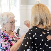 Two women chatting at event, one with back toward camera